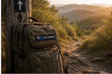 Load image into Gallery viewer, Flag name patch on a hiking backpack on a bush trail
